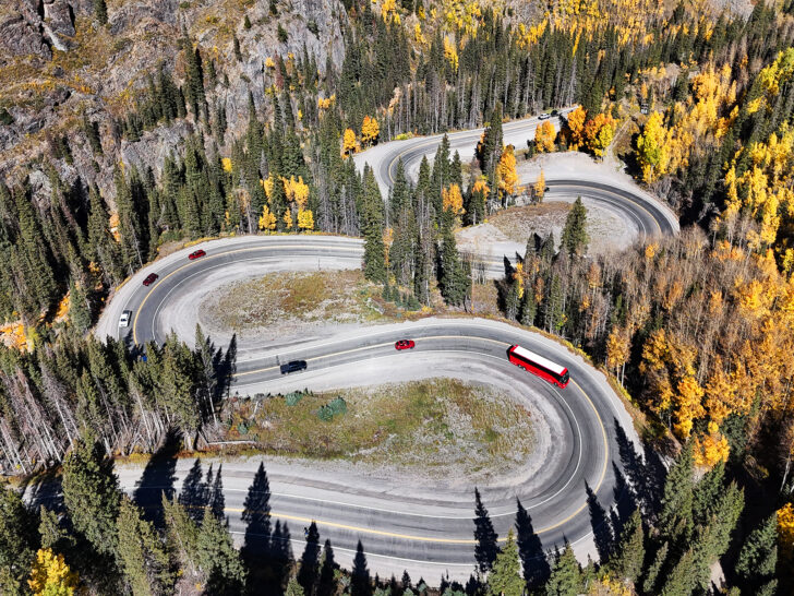 aerial view of red bus and cars on curvy road in Colorado