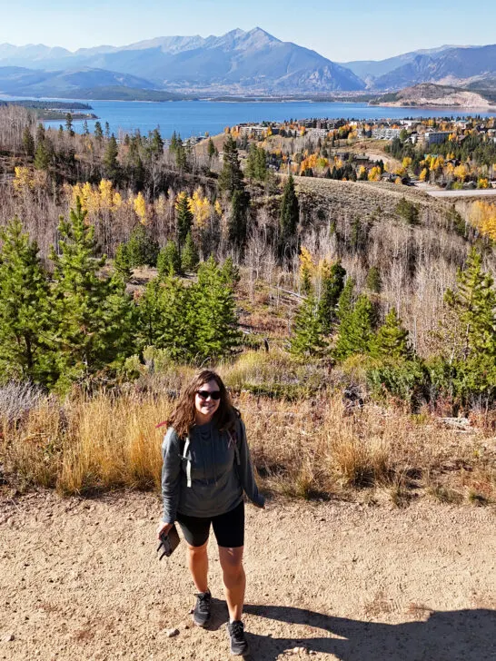 woman standing holding drone controller on hiking trail with mountain in distance