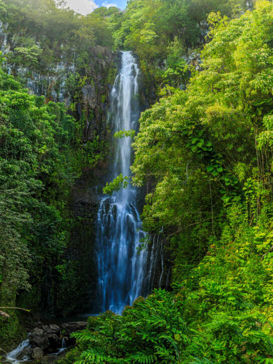 tall waterfall with trees surrounding it one of the best things to do in Hana Hawaii