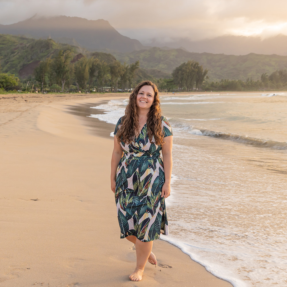 Nikki of She Saves She Travels standing on beach at dusk in green dress