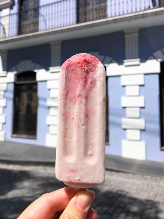 hand holding strawberry popsicle against purple building best restaurants in Old San Juan Puerto Rico