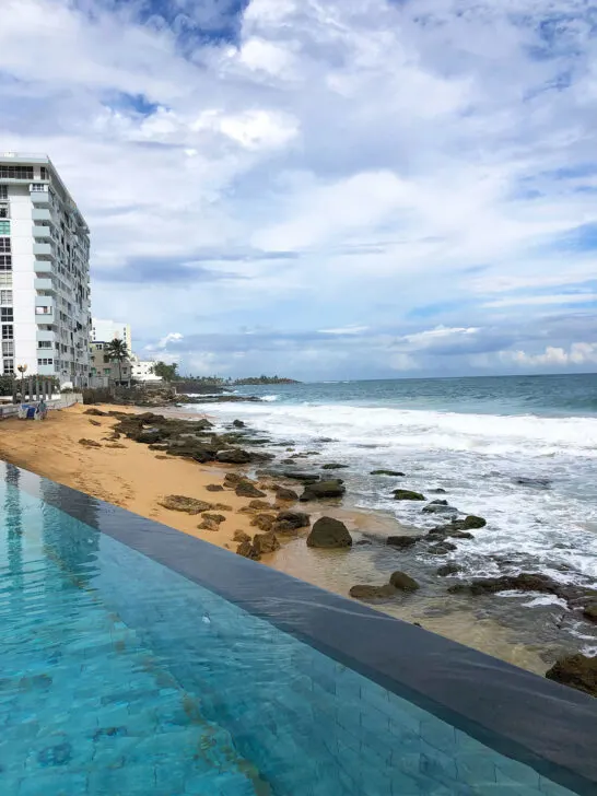 view of hotel pool in Condado with rocky shore and hotels in distance