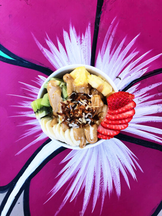 view of fruit bowl with peanut butter sitting on purple flower