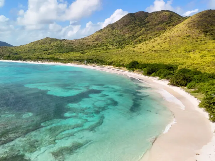 picturesque view of Jack Beach St. Croix USVI with teal water white sand and green hillside