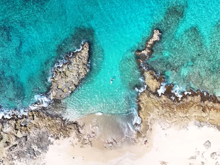 best beaches in St Croix aerial view of woman floating near beach and rocky shoreline