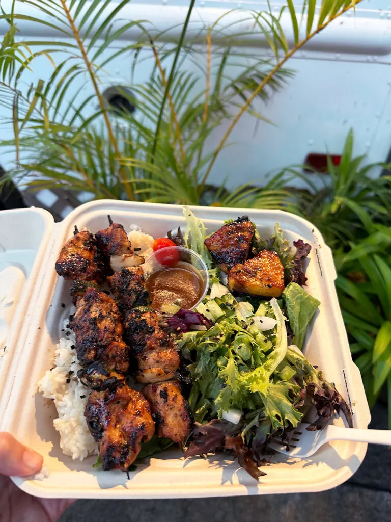 view of to go container of meat on skewers with salad best places to eat in Maui