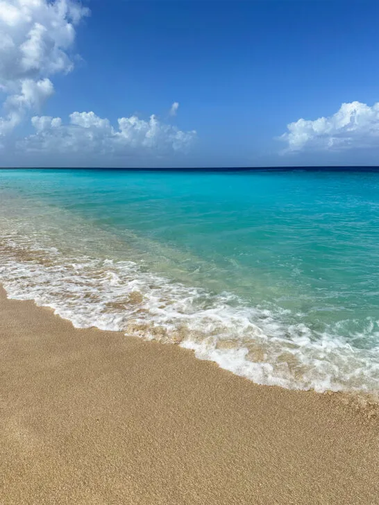 bright teal water with white wave and tan sand on sunny day best beaches in St Croix