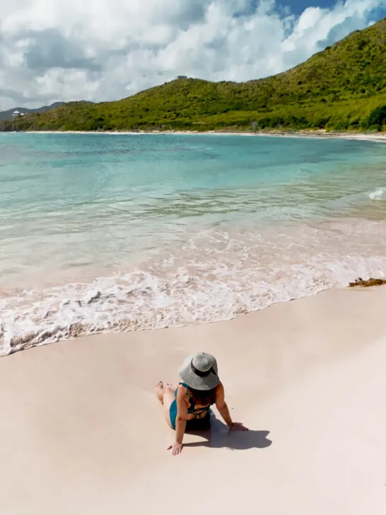 woman sitting on beach with pink sand blue water best beaches in St Croix