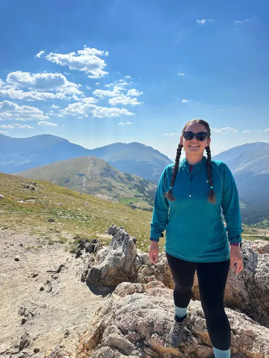 woman standing on rock with mountains in distance wearing hiking gear Colorado packing list summer
