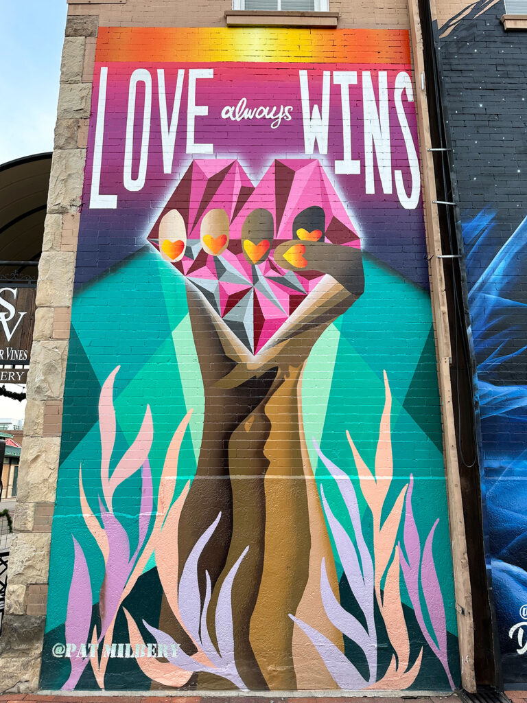 mural with hands and heart that reads love always wins