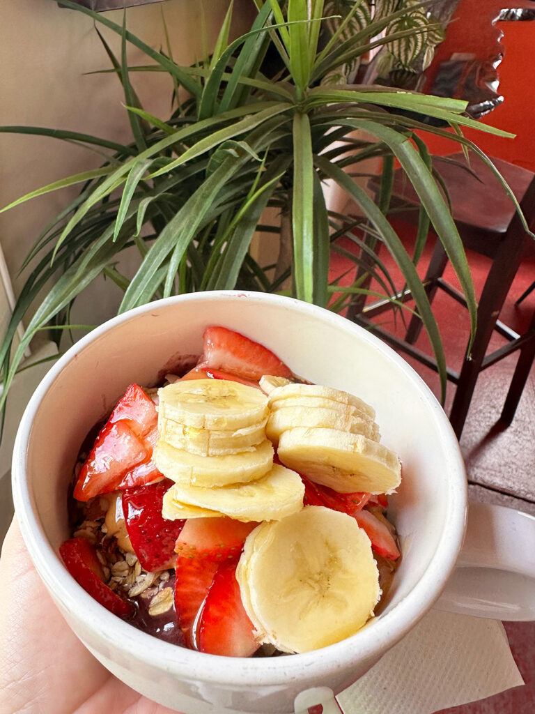 acai bowl with fresh fruit and palm tree in distance