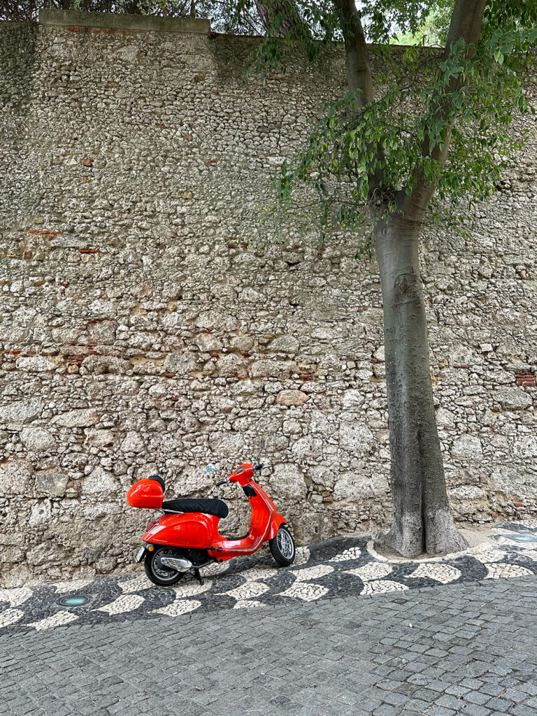 red vespa by tree and brick wall how to spend 3 days in Lisbon