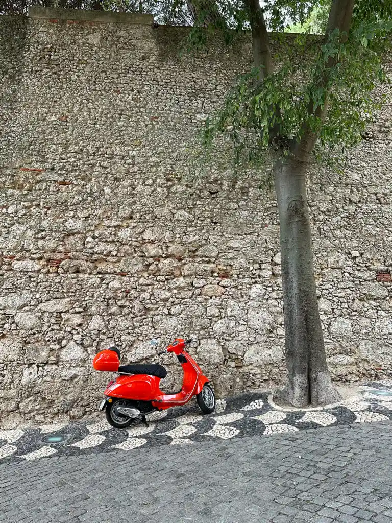 red vespa by tree and brick wall how to spend 3 days in Lisbon
