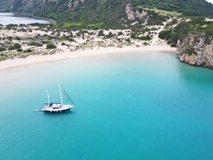 view of boat in the Gialova lagoon with bright blue water and hills in distance