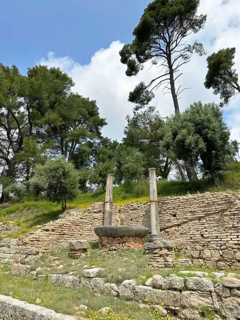 view of stone and original Olympic flame with trees behind 2 weeks in Greece itinerary