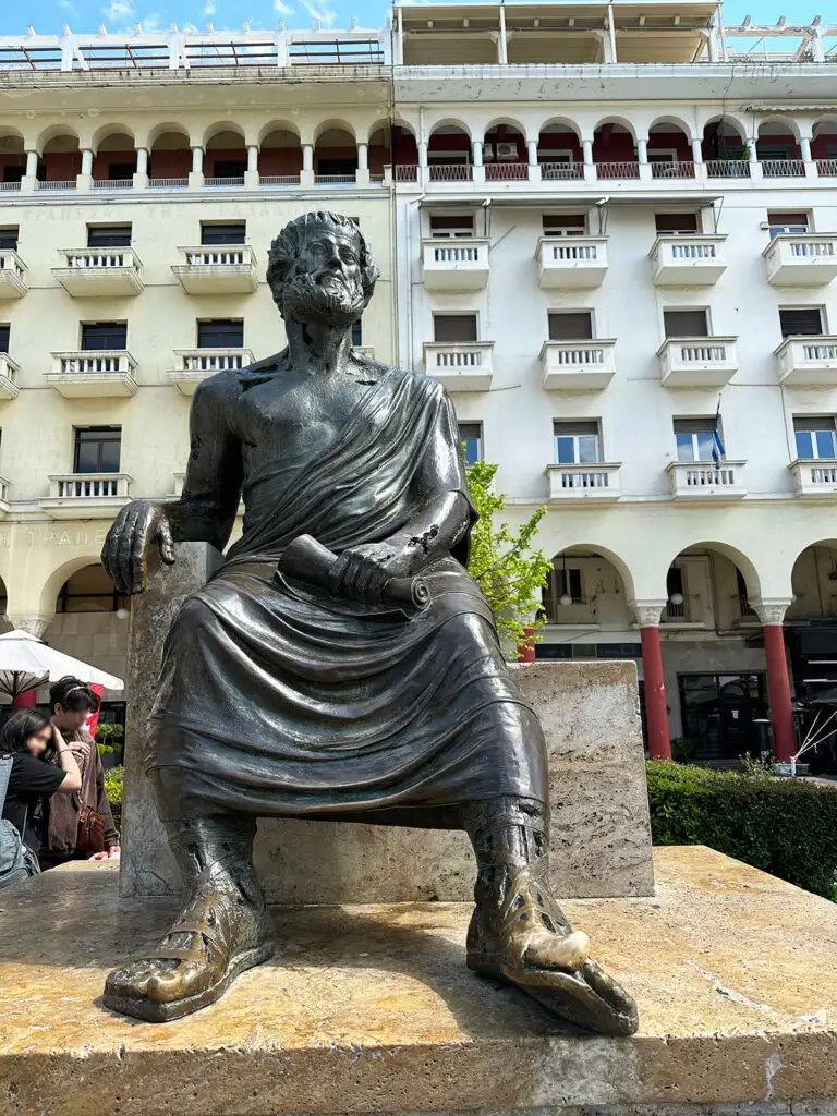 view of statue of Aristotle looking in distance with modern buildings behind