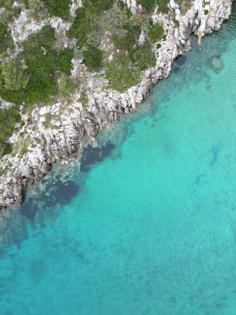 gorgeous teal water with white rocky coastline and with green shrubs