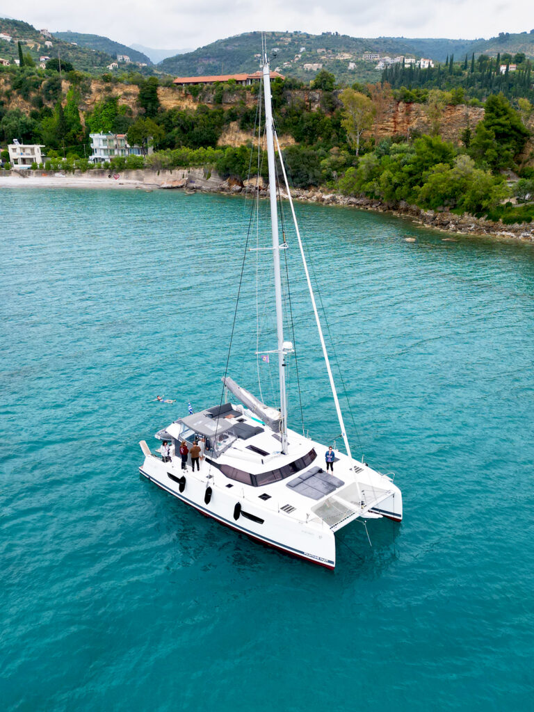best itinerary greece drone view of catamaran on blue water with rolling hills behind