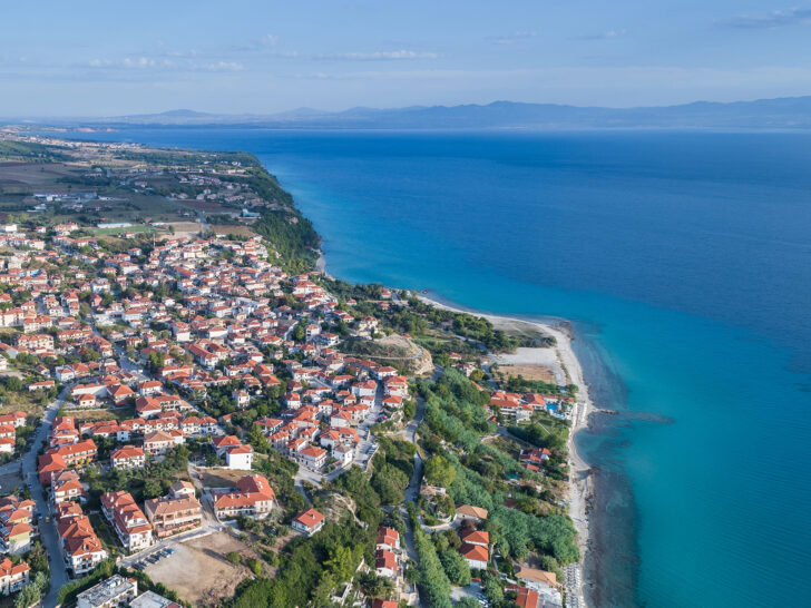aerial view of village with orange roofs and beach with blue ocean Greece mainland itinerary
