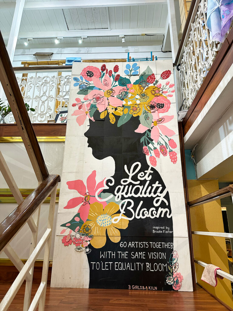 sign with flowers and words that say let equality bloom with artist info