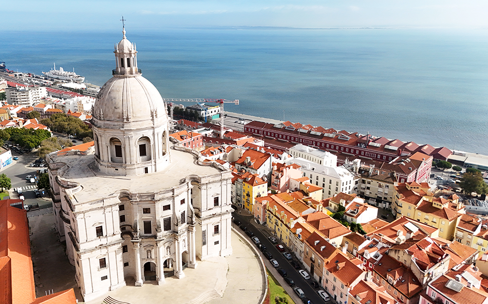 Portugal travel guides view of white building and cityscape in Lisbon with orange roof tops and water in distance