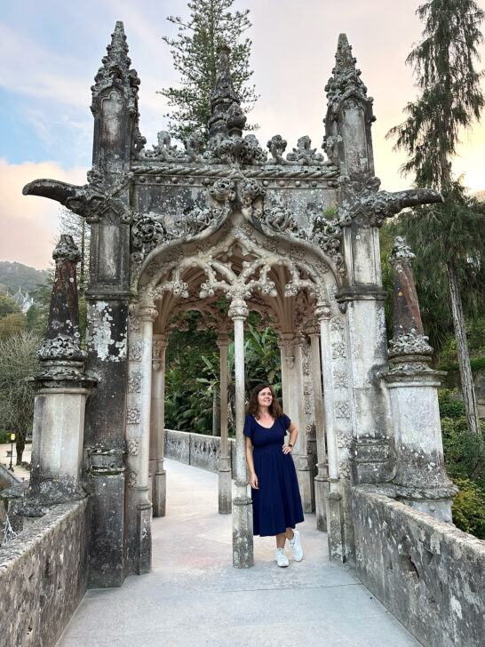 woman in blue dress standing in doorway of castle arch