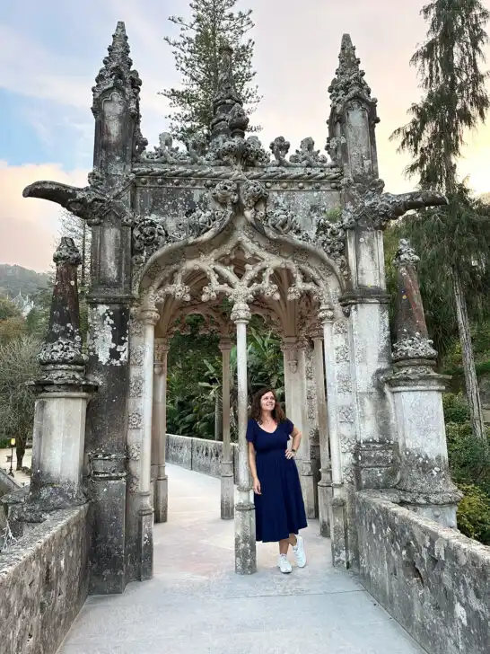 woman in blue dress standing in doorway of castle arch