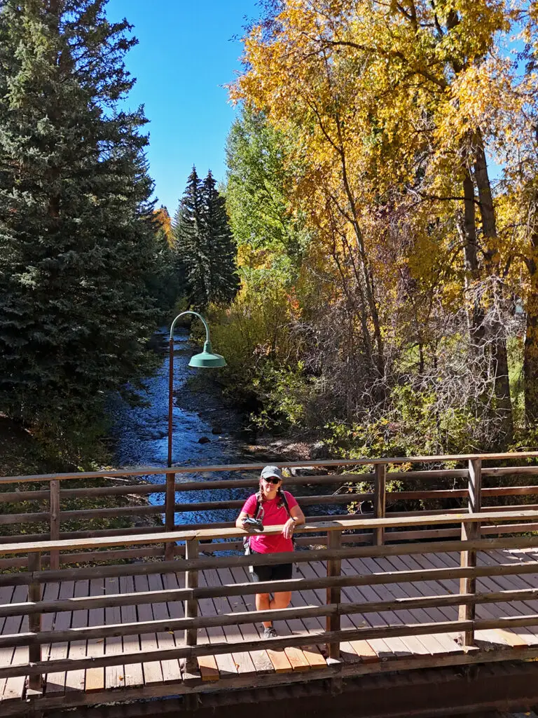 woman in pink shirt standing on bridge with river in distance