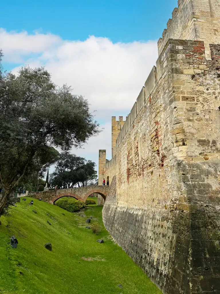 view of castle wall with bridge and trees
