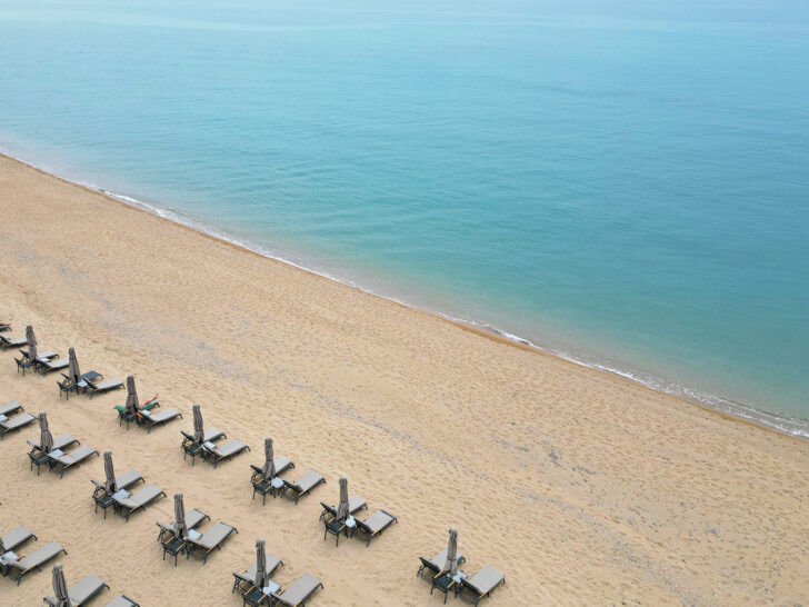 view of blue water tan sand and chairs