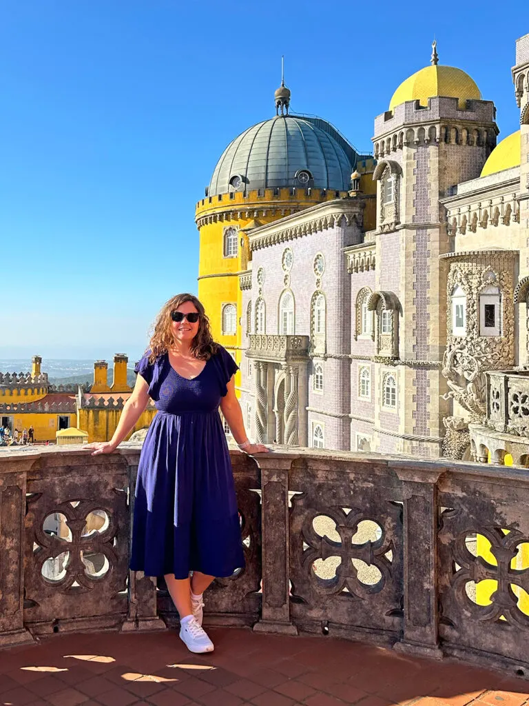 woman in blue dress standing in front of castle near Lisbon Portugal