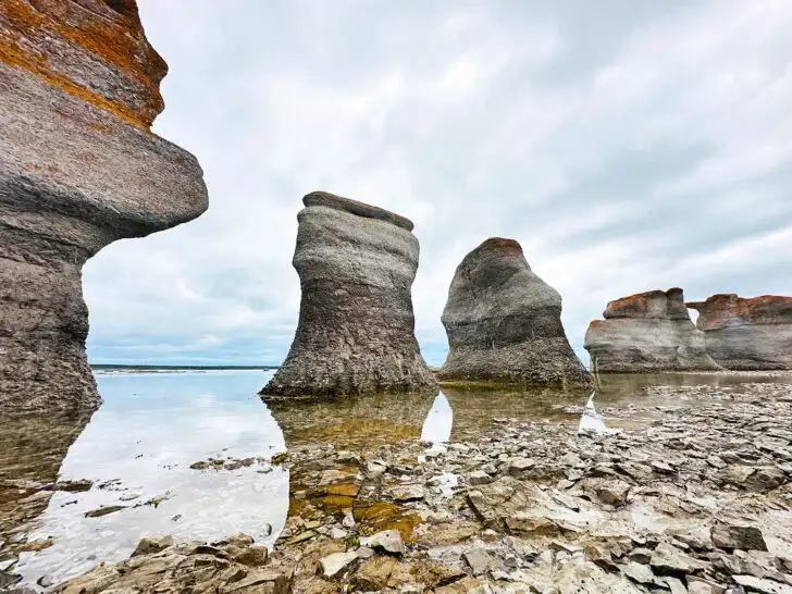 Mingan Archipelago National Park Reserve view of large monoliths with rocky base and blue gray sky with water reflection