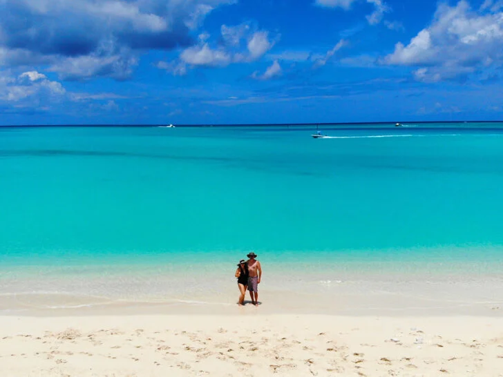 Caribbean drone photos of a couple standing on beach with teal water behind on bright sunny day in turks and caicos
