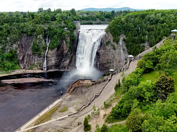 drone view of waterfall with walkway and water falling off cliff