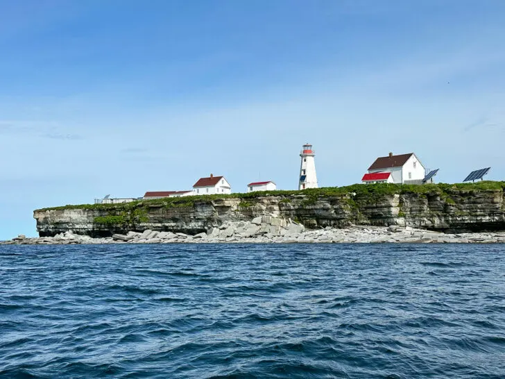 Cote Nord Quebec island with buildings and lighthouse reasons to visit cote Nord Quebec